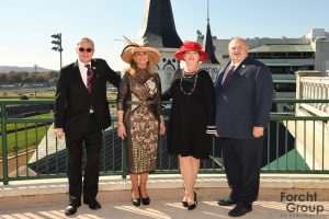 2 women and 2 men standing in the sun shine with the twin spires behind them