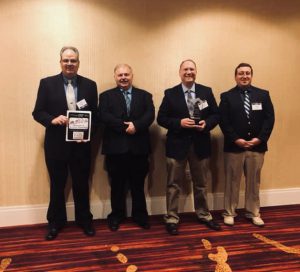 journal: four men dressed in suits holding an award