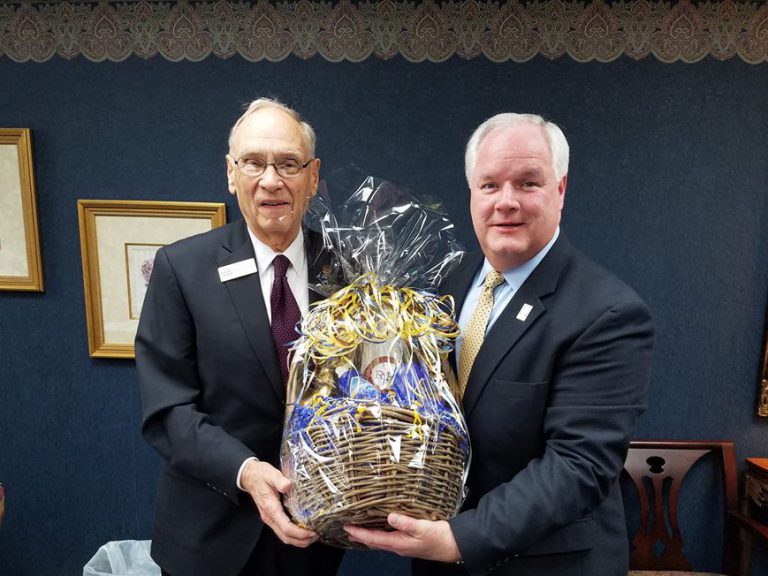Forcht Broadcasting: two men in suits holding a basket smiling at the camera