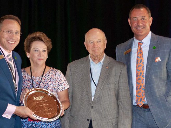 Small Business: three men and a woman smiling at the camera holding a trophy
