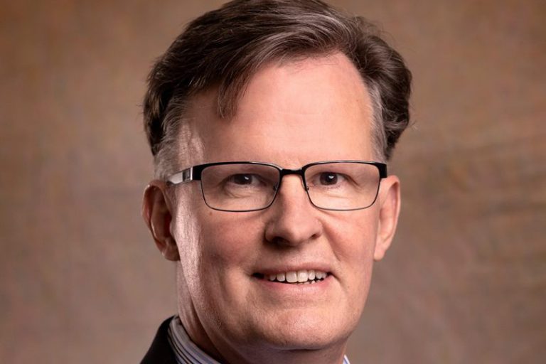 President: a man in a suit smiling at the camera