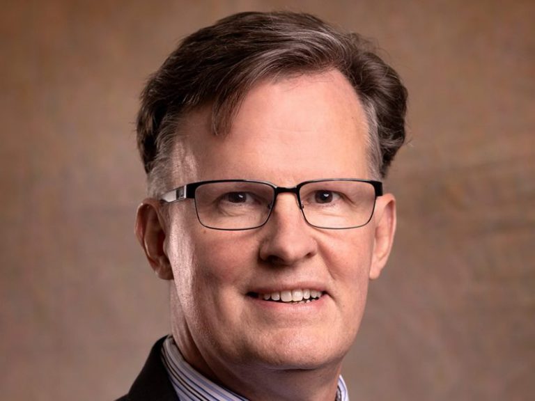 President: a man in a suit smiling at the camera