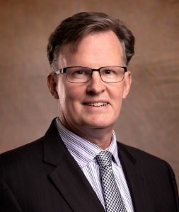 President: a man in a suit smiling at the camera