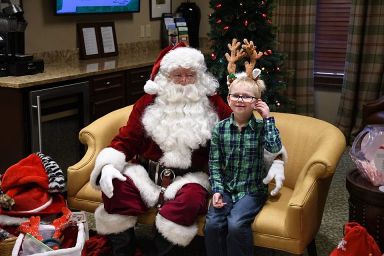 santa sitting with a young boy wearing antlers