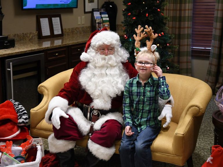 santa sitting with a young boy wearing antlers